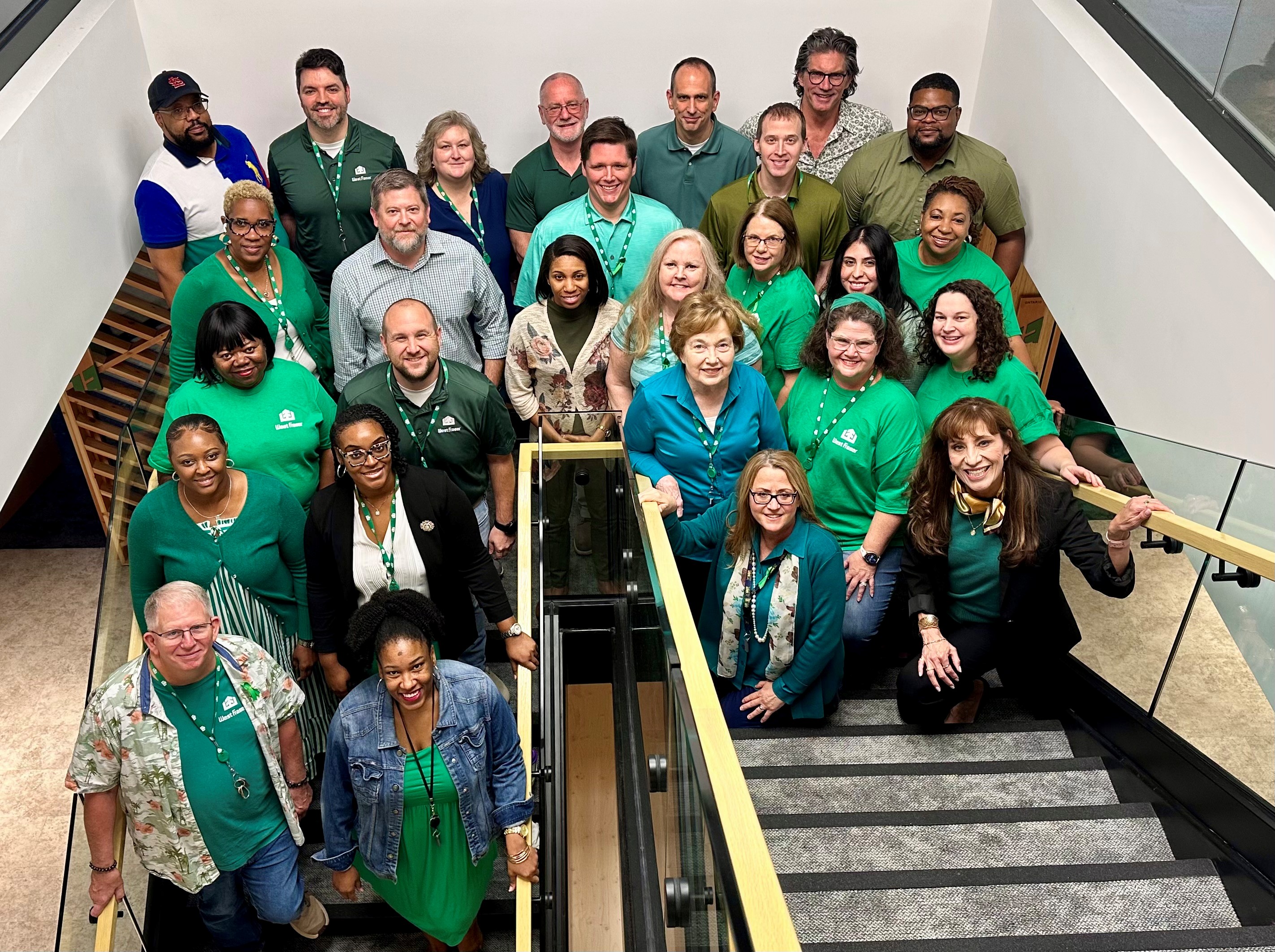 West Fraser Memphis office team members wearing green post for a photo in the office's staircase.  