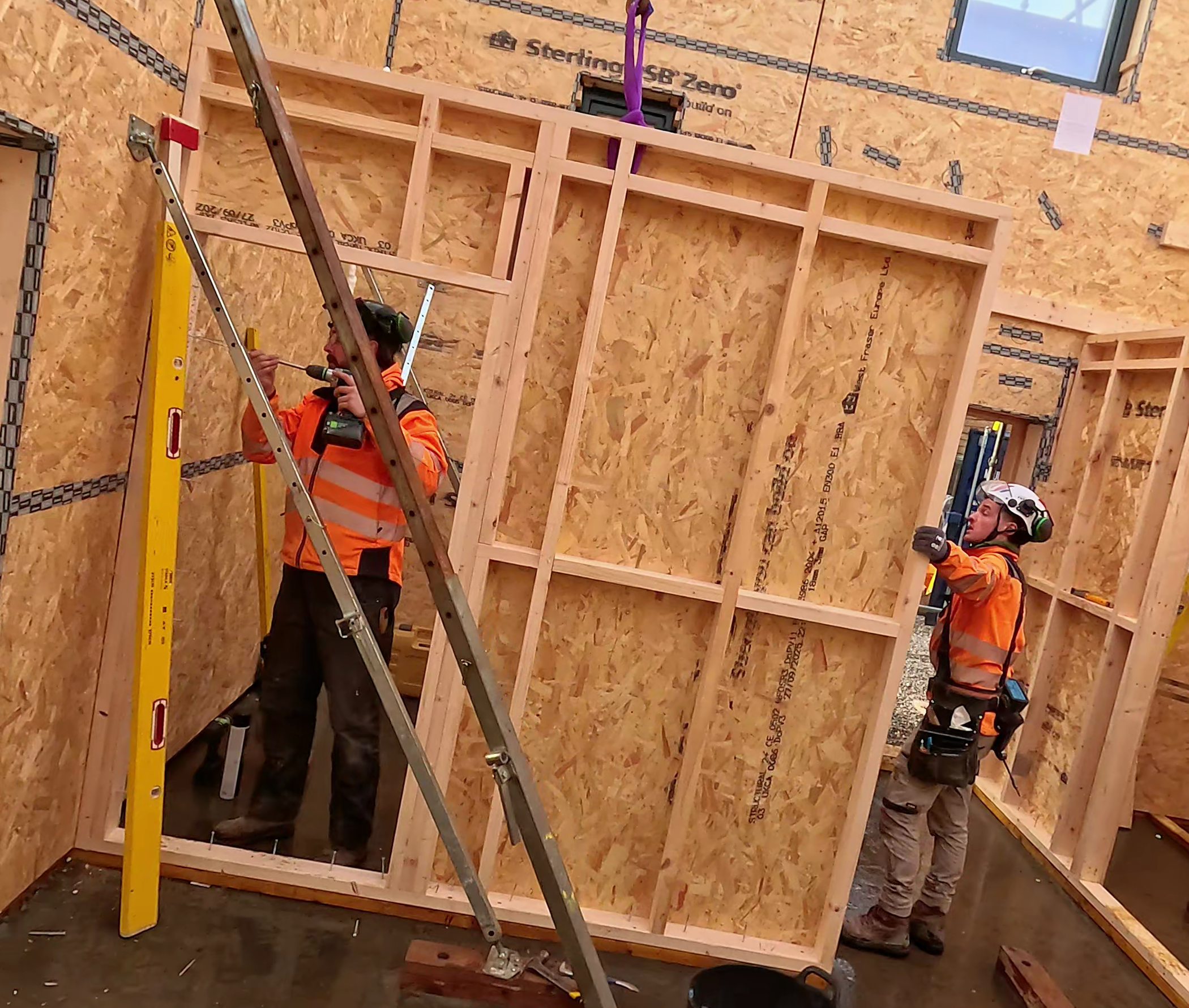 Workers in PPE install West Fraser OSB panels during the construction of a new home.